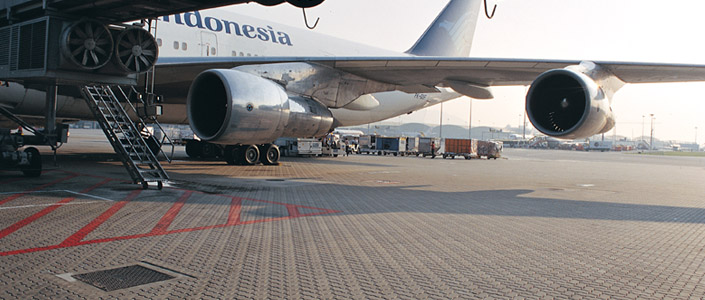 A photo of a large airplane sitting on a concrete paving block surface at an airport.